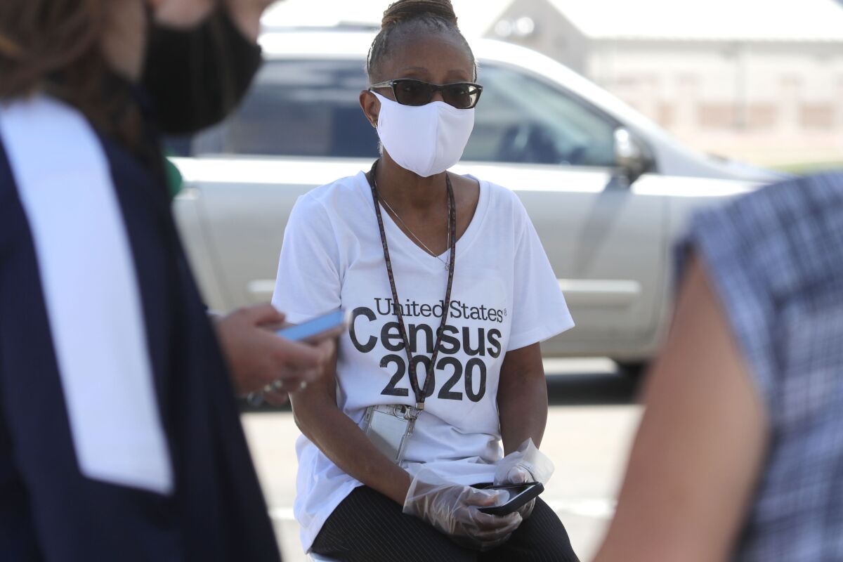 Amid concerns of the spread of COVID-19, census worker Jennifer Pope wears a mask and sits by ready to help at a U.S. Census walk-up counting site set up for Hunt County in Greenville, Texas, Friday, July 31, 2020. (AP Photo/LM Otero)