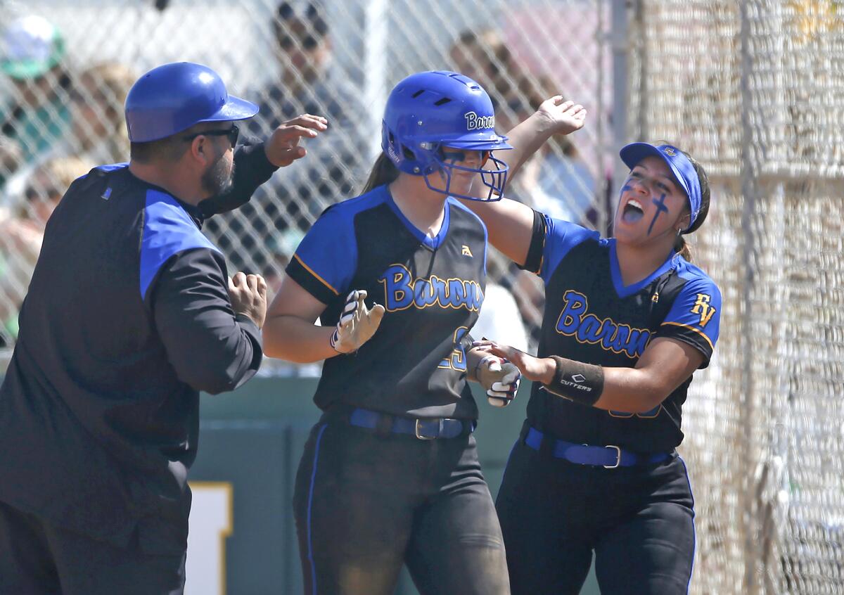 Fountain Valley's Jenna Bixler, center, is congratulated at home after scoring the game's first run against Edison.