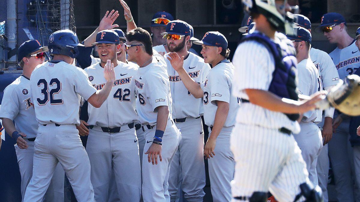 Cal State Fullerton's Jairus Richards (32) is congratulated by teammates after scoring a run against Washington in the fifth inning Saturday.