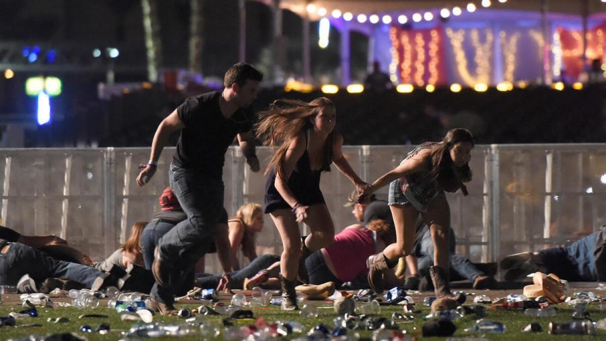People run from the Route 91 Harvest country music festival after hearing gunfire Sunday night in Las Vegas. More than 50 people have died and another 500 are injured.
