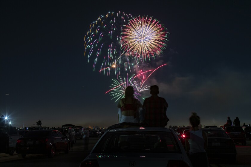 A couple on the roof of their car watch fireworks.