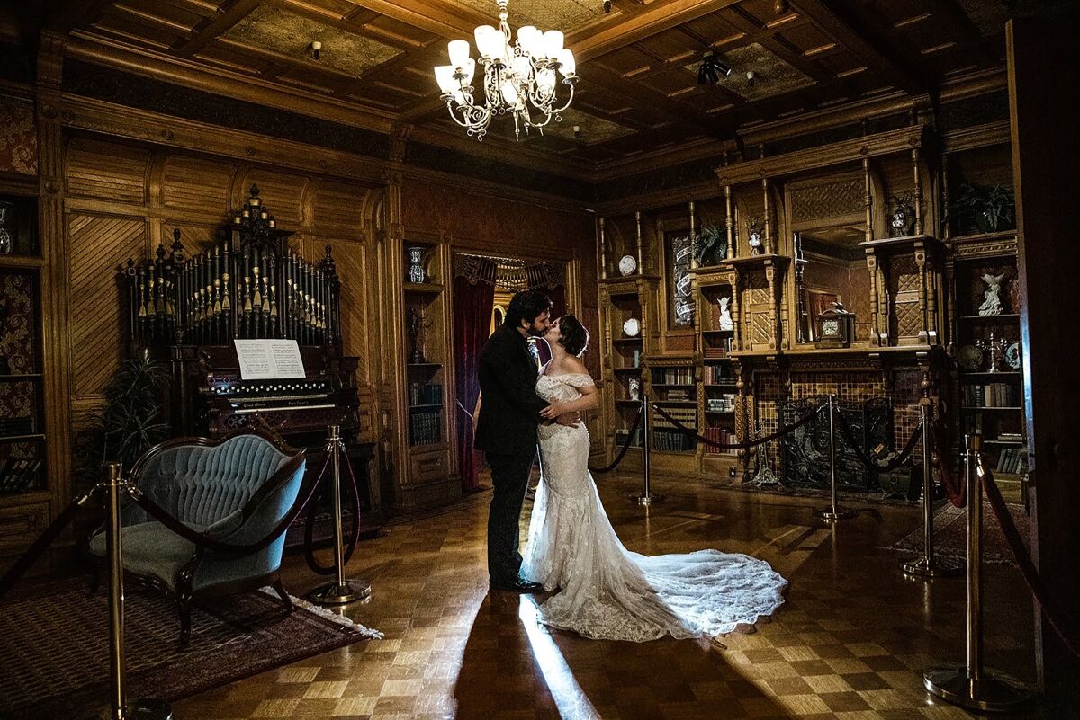 A bride and groom kiss inside a room of the Winchester Mystery House in San Jose.