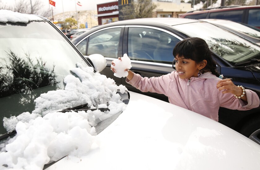 Vatsika Viswanathan, 8, grabs snow from the hood of a car