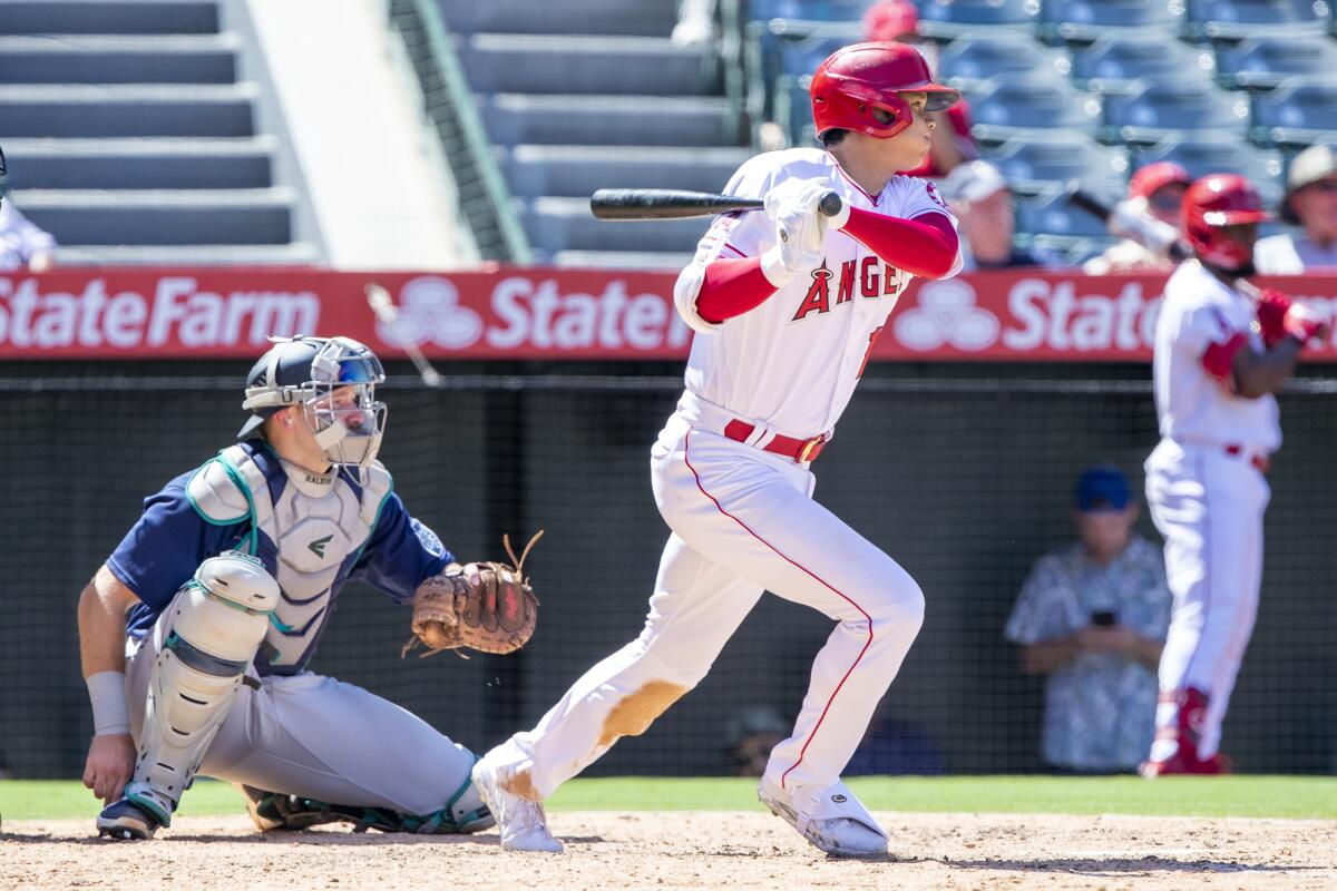 Angels designated hitter Shohei Ohtani hits an RBI single as Seattle Mariners catcher Cal Raleigh looks on.