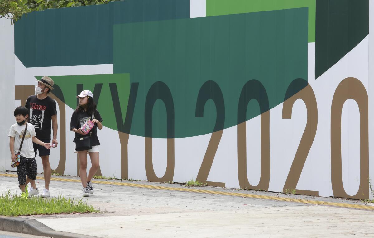 People walk by posters to promote Tokyo 2020 Olympics in Tokyo, Wednesday, July 14, 2021. The Olympic Games are scheduled to begin on July 23. (AP Photo/Koji Sasahara)