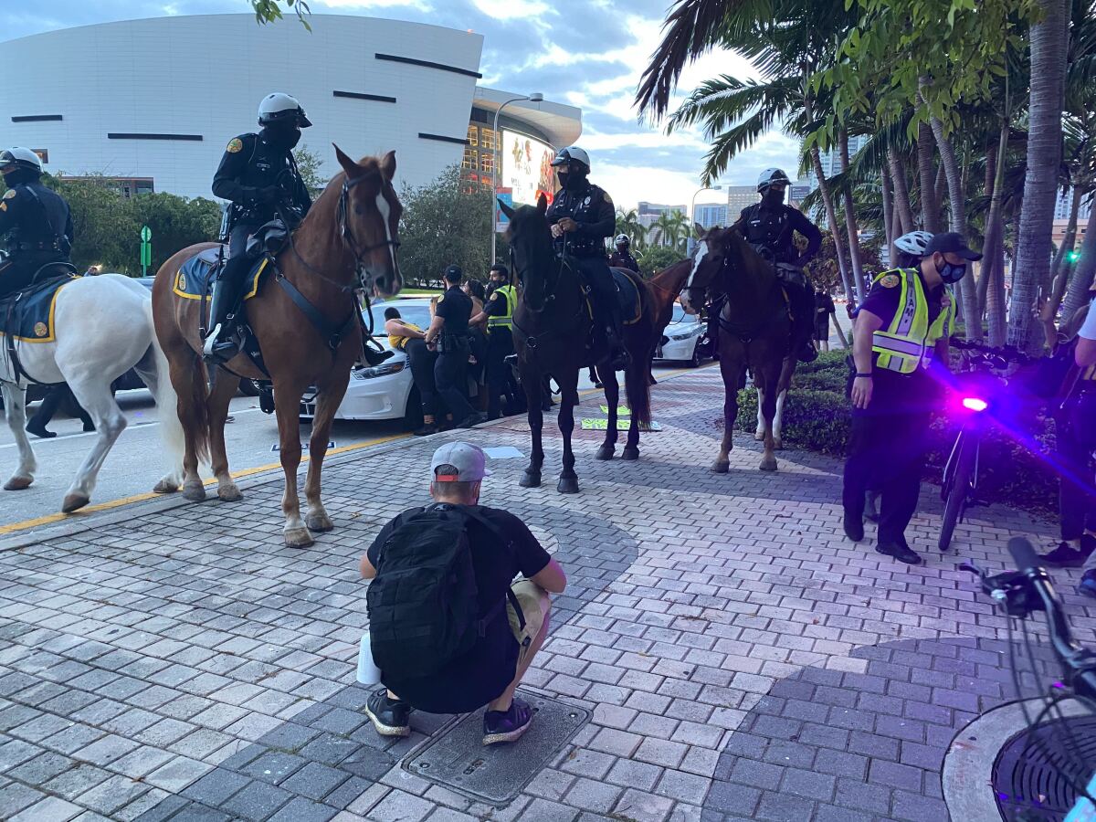 Police on horseback in front of a person being arrested in Miami. 