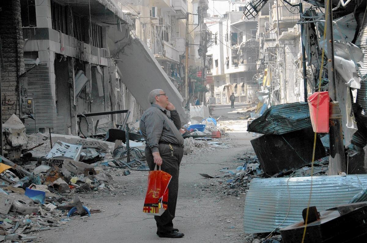 A resident takes in the destruction in Homs, Syria, where the remaining rebels left the Old City last week.