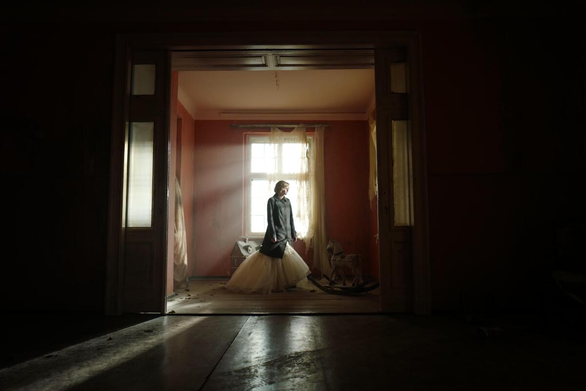 A woman in a dark room illuminated by sun shining through a window