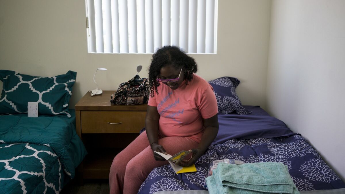 Dorothy Latham reads a welcome card left on her bed as she and other tenants move into their new home in South Los Angeles. "Oh, wow. This is really nice," she said.