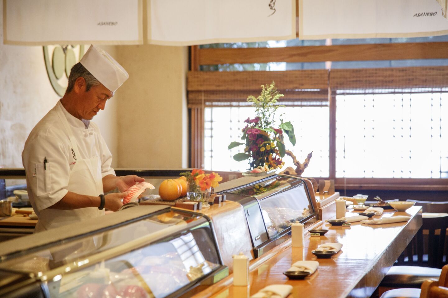 Chef Tetsuya Nakao preparing fish behind the counter.