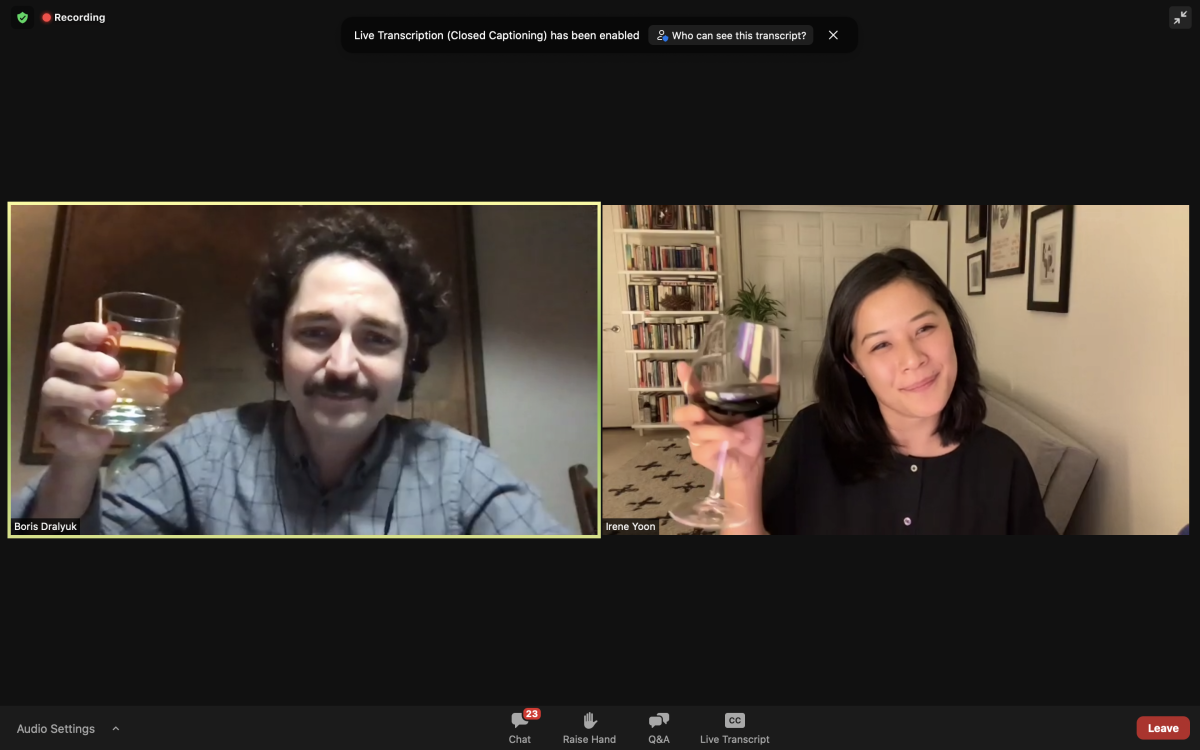Two people on Zoom raise their glasses