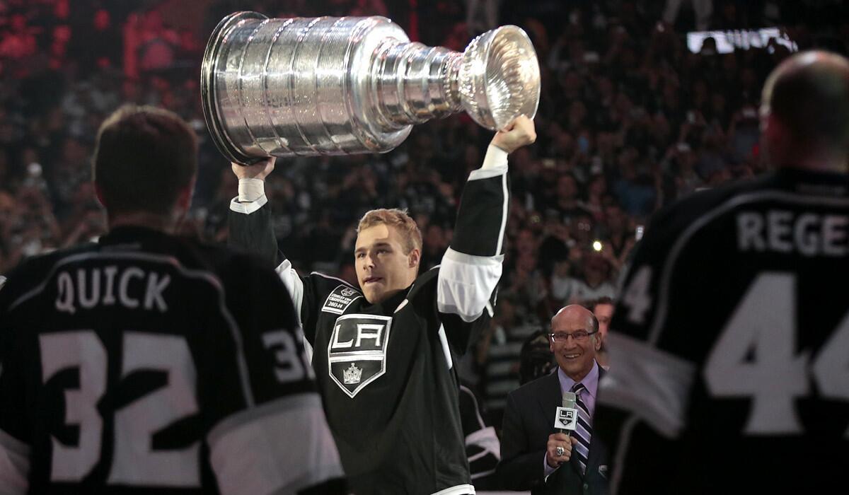 Kings captain Dustin Brown hoists the Stanley Cup overhead to show fans at Staples Center during the team's championship banner ceremony.