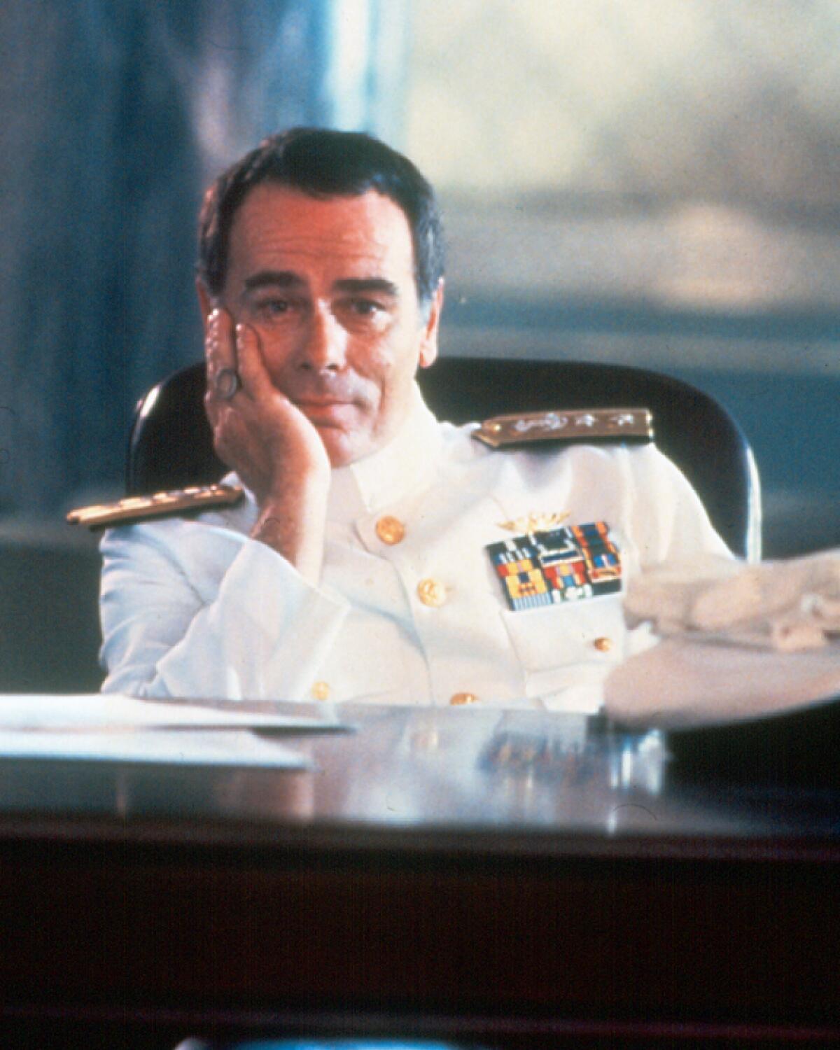 A man dressed as an admiral sitting behind a desk