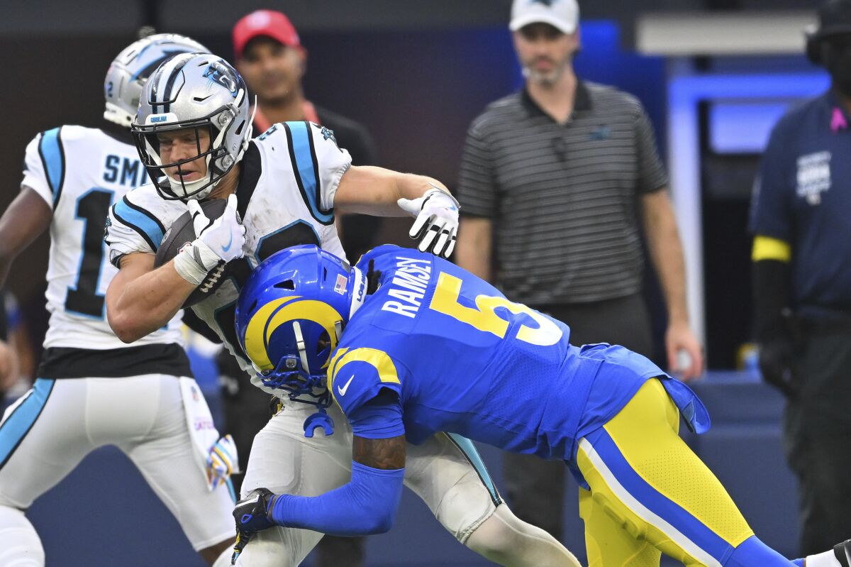 Carolina Panthers running back Christian McCaffrey, left, is tackled by Rams cornerback Jalen Ramsey.