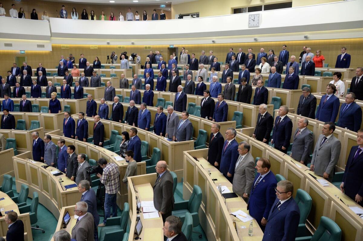Members of Russia's Federation Council stand as the national anthem is played Wednesday. The upper chamber of parliament voted to scrap a resolution allowing Russian President Vladimir Putin to send troops into Ukraine.
