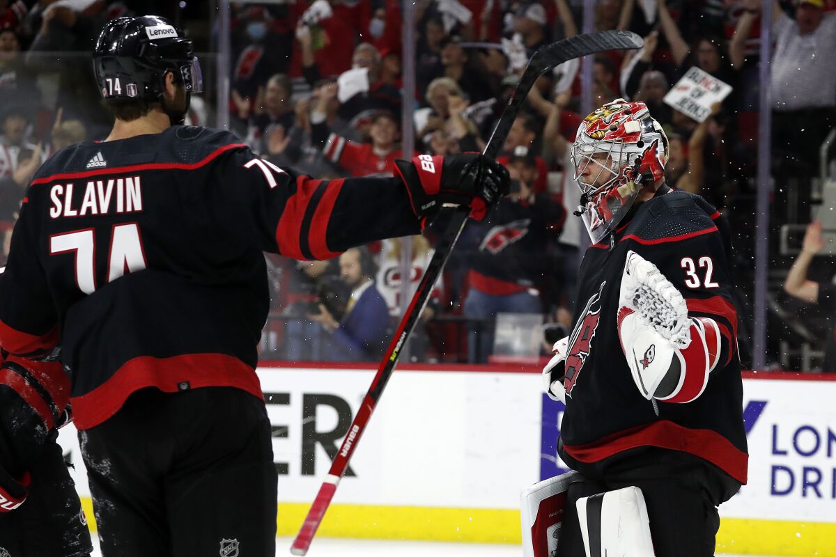 Carolina Hurricanes goaltender Antti Raanta (32) celebrates with teammate Jaccob Slavin (74) following their win over the Boston Bruins in Game 7 of an NHL hockey Stanley Cup first-round playoff series in Raleigh, N.C., Saturday, May 14, 2022. (AP Photo/Karl B DeBlaker)