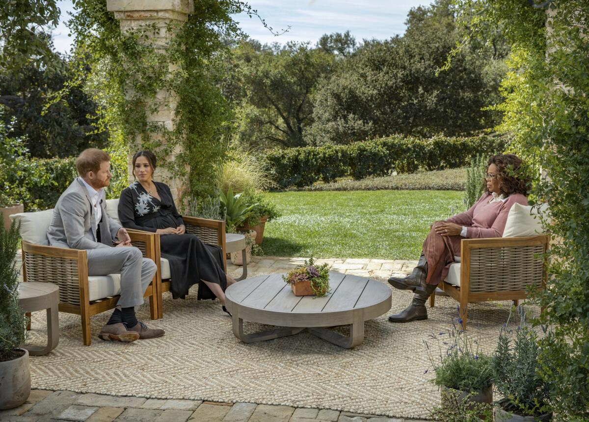 Prince Harry, Meghan and Oprah Winfrey sit in chairs on a patio in Montecito.