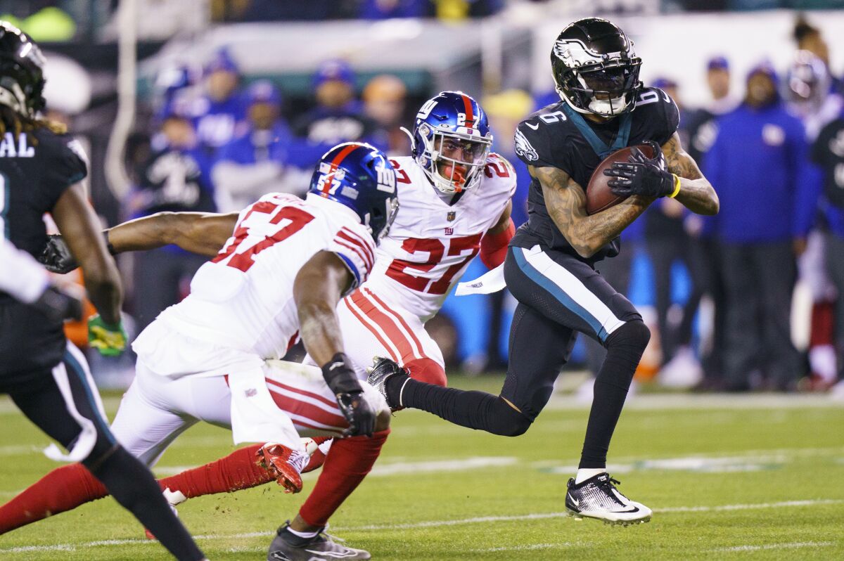 Eagles alıcısı DeVonta Smith (6), Giants Jarrad Davis'i (57) ve güvenlik Jason Pinnock'u geçiyor.