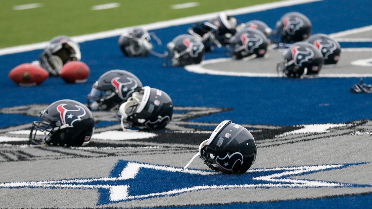 Several Houston Texans helmets sit over the Dallas Cowboys logo in an end zone at the Cowboys training facility on Aug. 28.