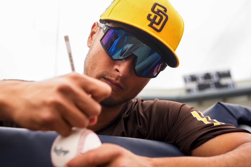 San Diego Padres starting pitcher Yu Darvish, of Japan, signs a baseball before a spring training baseball game against the Cleveland Guardians, Monday, Feb. 26, 2024, in Peoria, Ariz. (AP Photo/Lindsey Wasson)