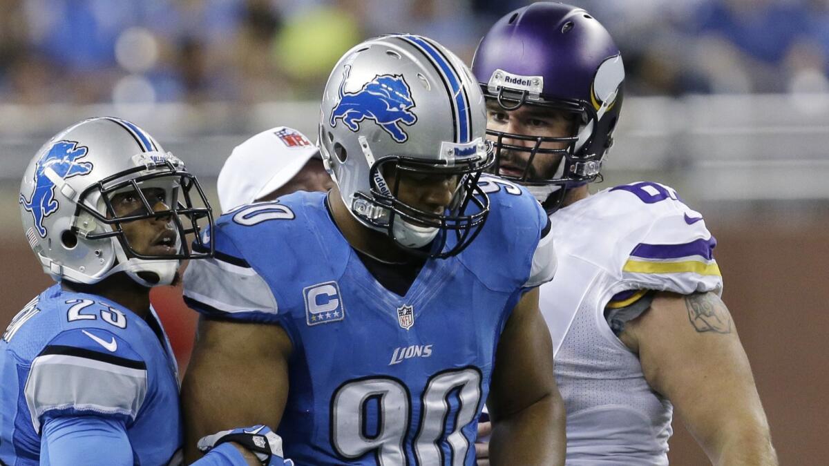 Detroit Lions defensive tackle Ndamukong Suh (90) walks away after his hit on Minnesota Vikings center John Sullivan, right, during the first half of a game at Ford Field in Detroit in 2013.