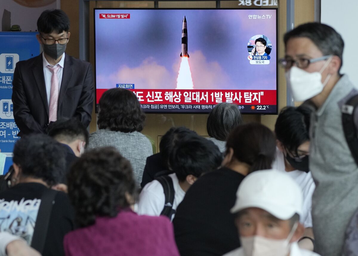 People are seated inside near a TV screen that shows a missile ascending