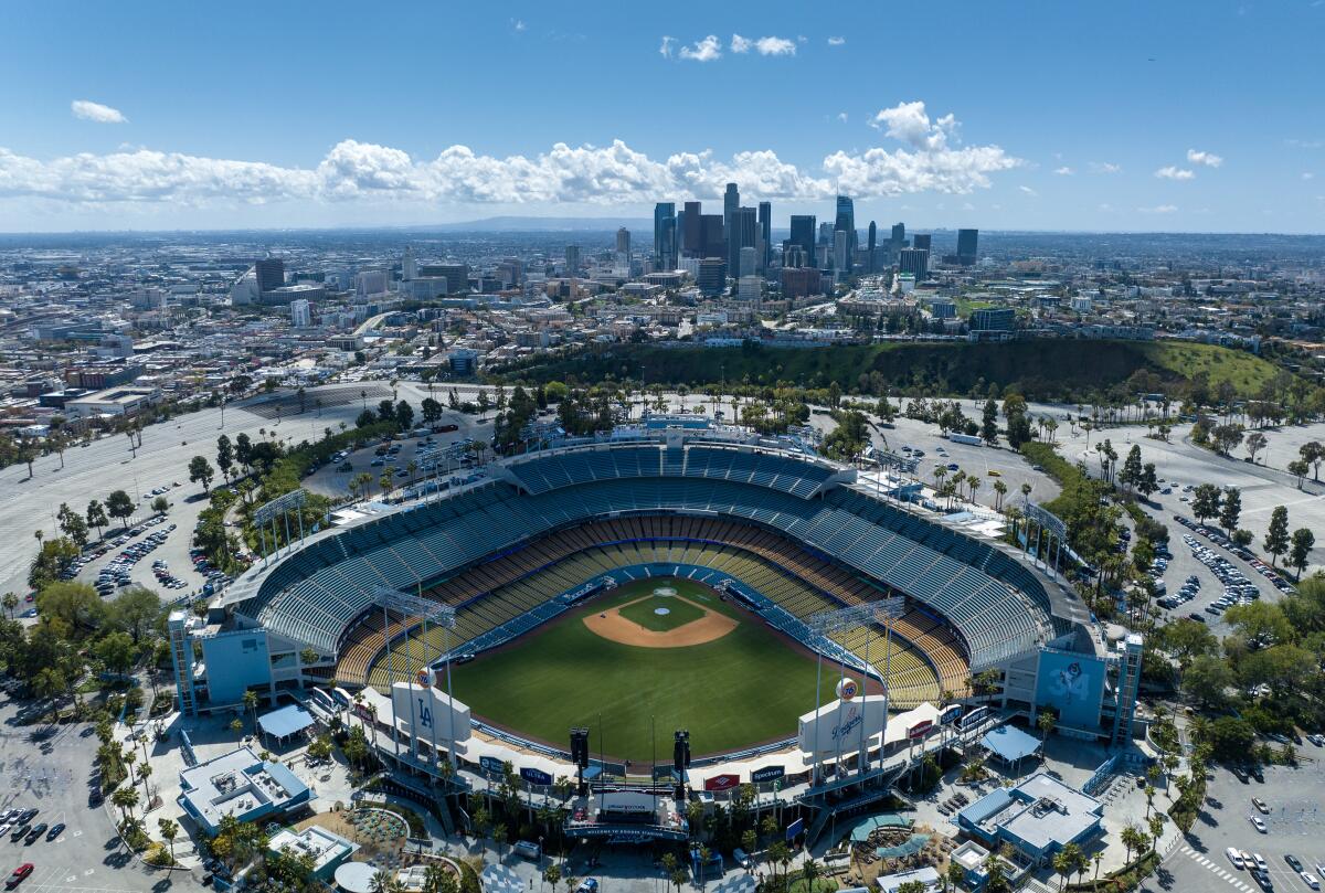 An aerial vuiew of the Dodger Stadium with the Los Angeles skyline on the horizon
