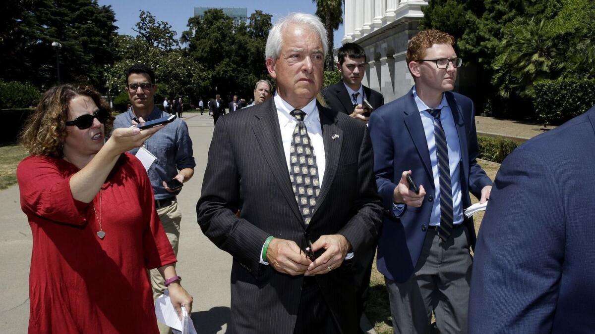 John Cox, center, is questioned by reporters as he leaves a June news conference where he blasted a recent gas tax increase.