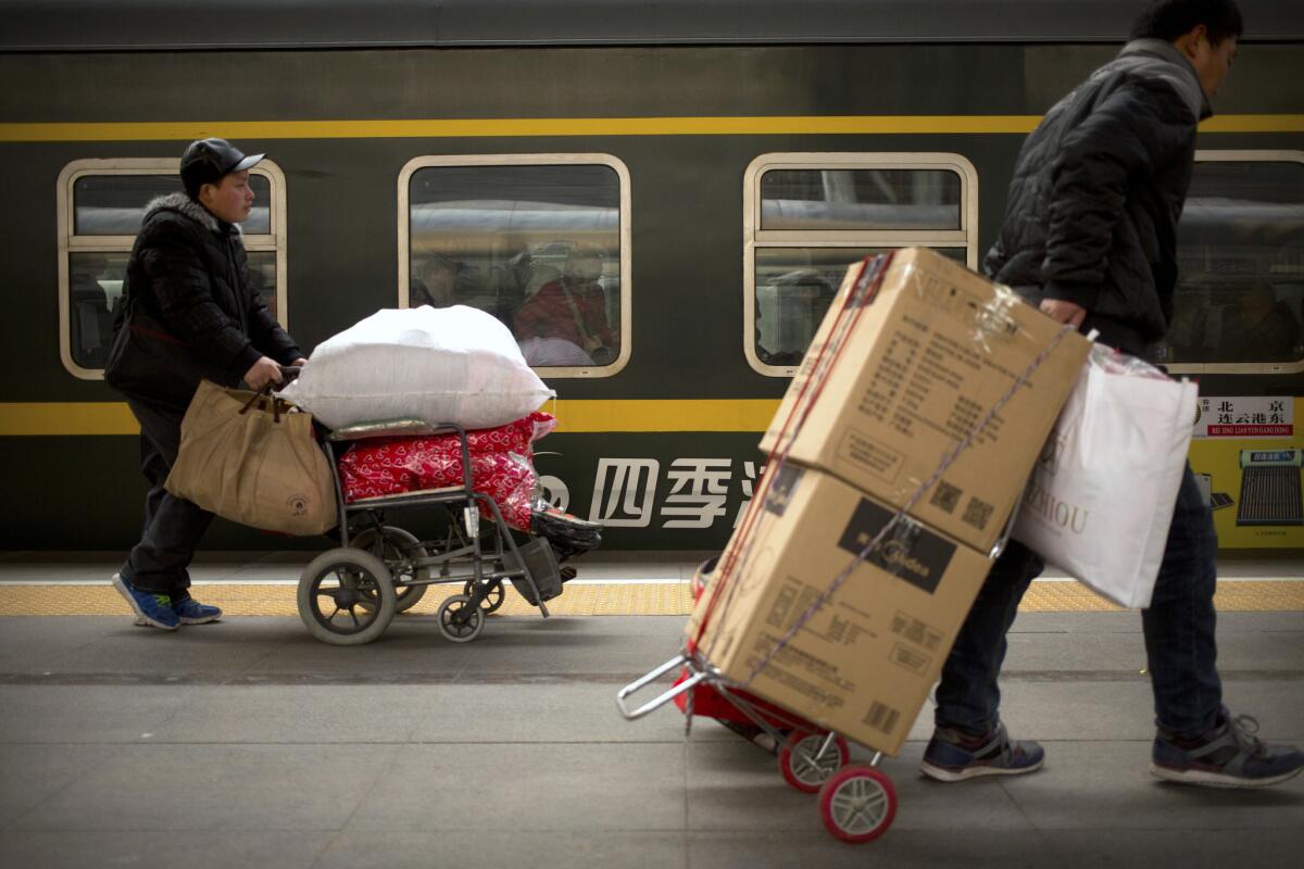 Passengers wheel their luggage as they board a train at the Beijing Railway Station in Beijing. China's peak travel season is kicking into high gear as hundreds of millions of people return home for Spring Festival celebrations or head for vacation destinations.