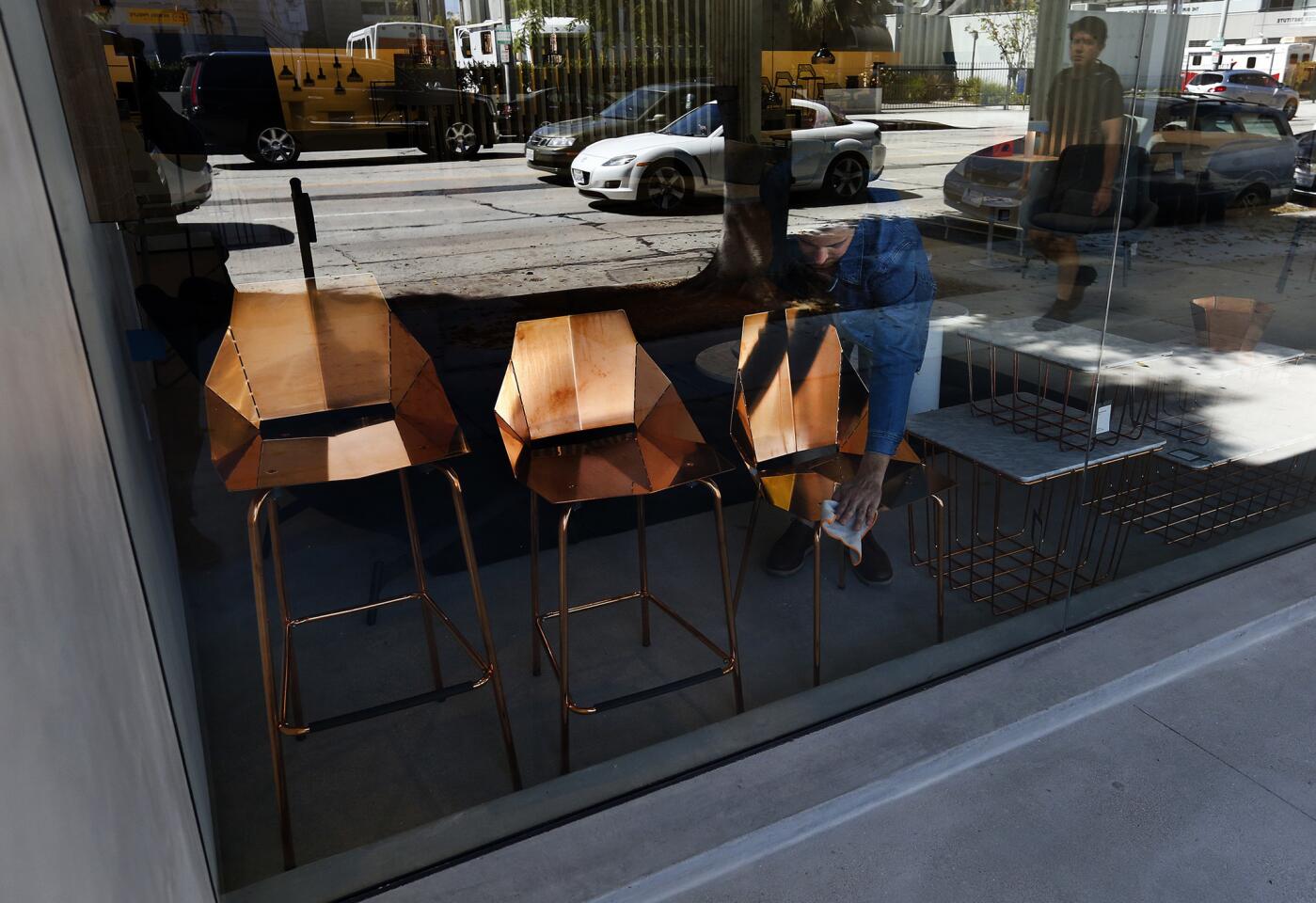 Design Sales' Josiah Johnson dusts a Copper Real Good bar stool, counter stool and chair that are part of the window display at the new Blu Dot store in West Hollywood.
