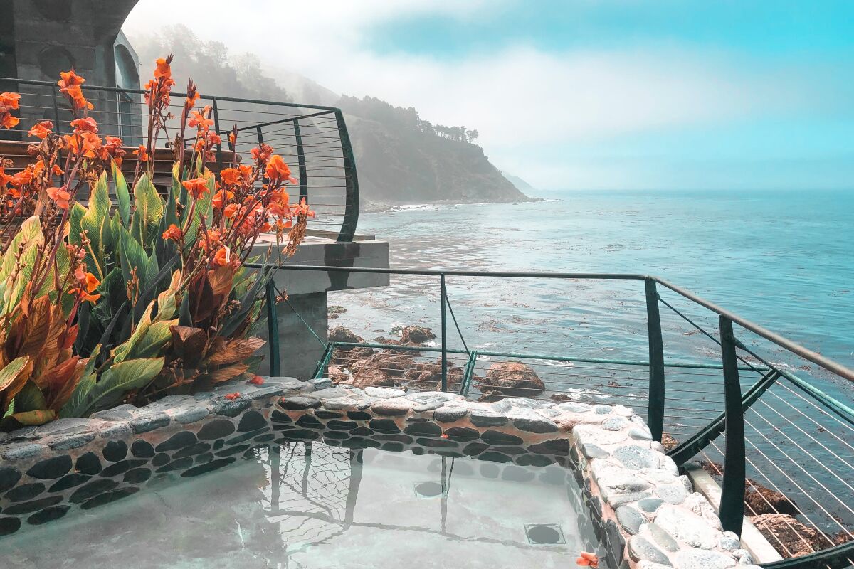 Stone-walled baths bubble at Esalen, Big Sur, with cliffs and sea beyond and flowering canna alongside.
