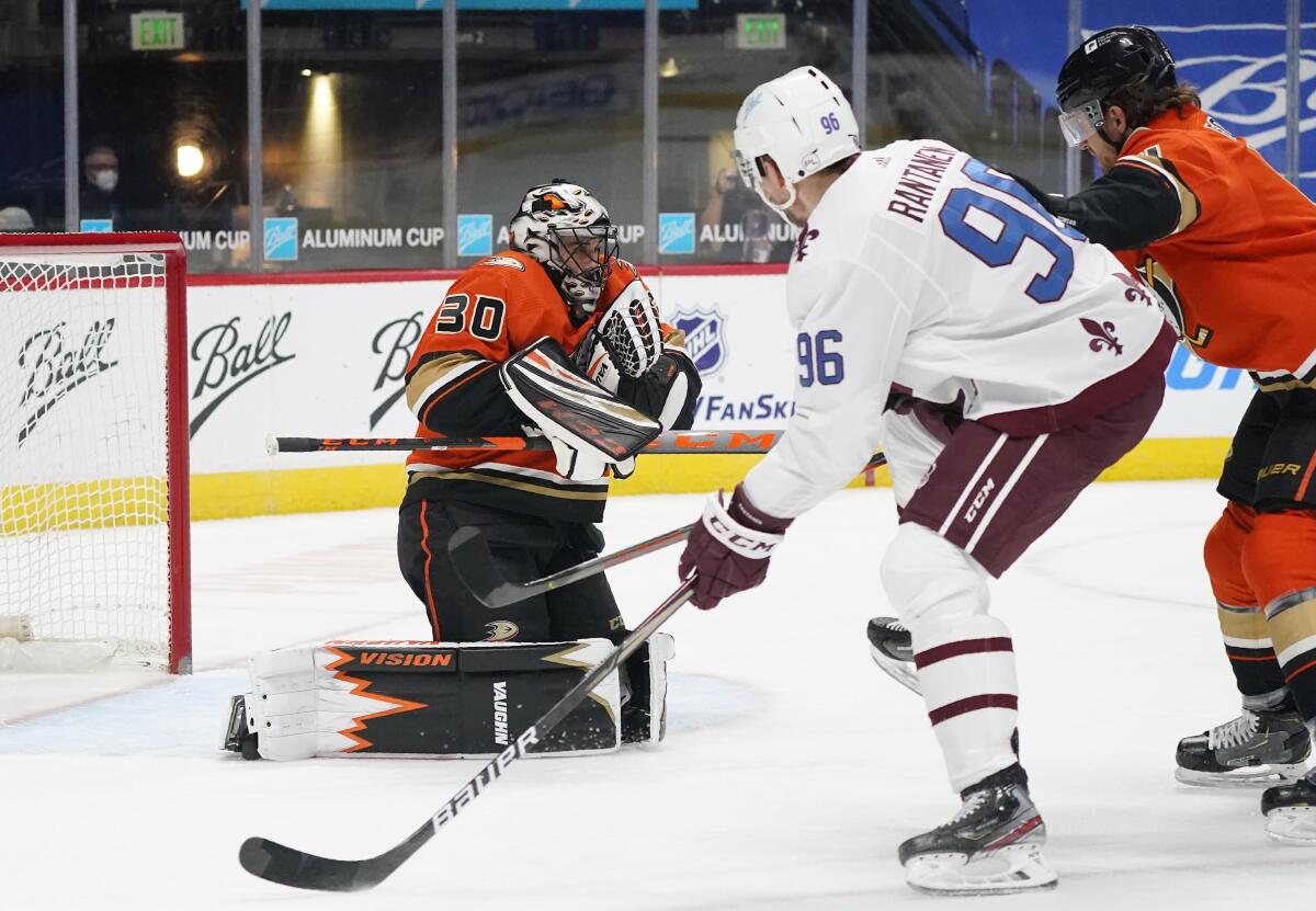 Anaheim Ducks goaltender Ryan Miller, left, stops a shot by Colorado Avalanche right wing Valeri Nichushkin, center, as Ducks' Hampus Lindholm defends during the first period of an NHL hockey game Saturday, March 6, 2021, in Denver. (AP Photo/David Zalubowski)