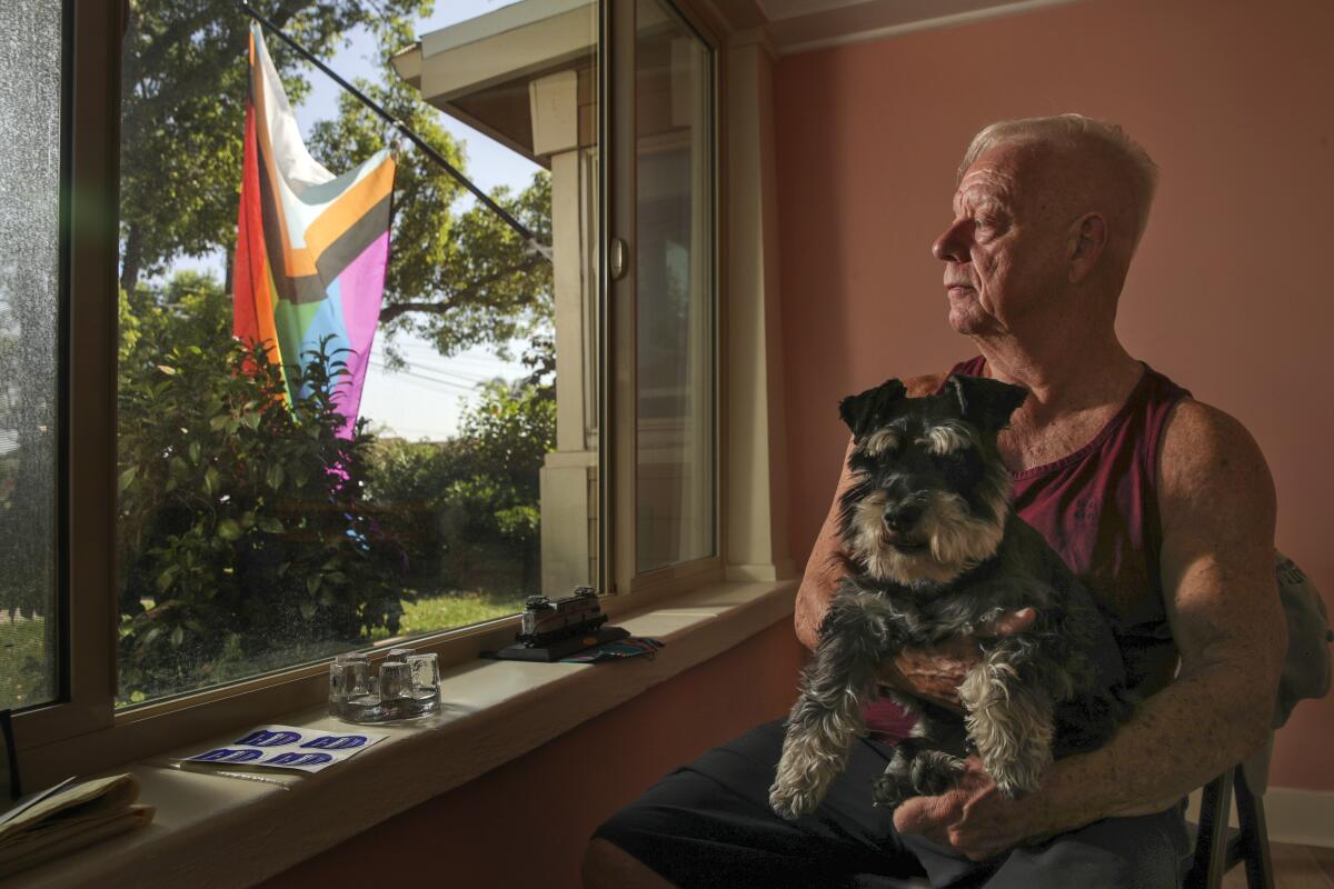 A man holds a dog while sitting in a chair.