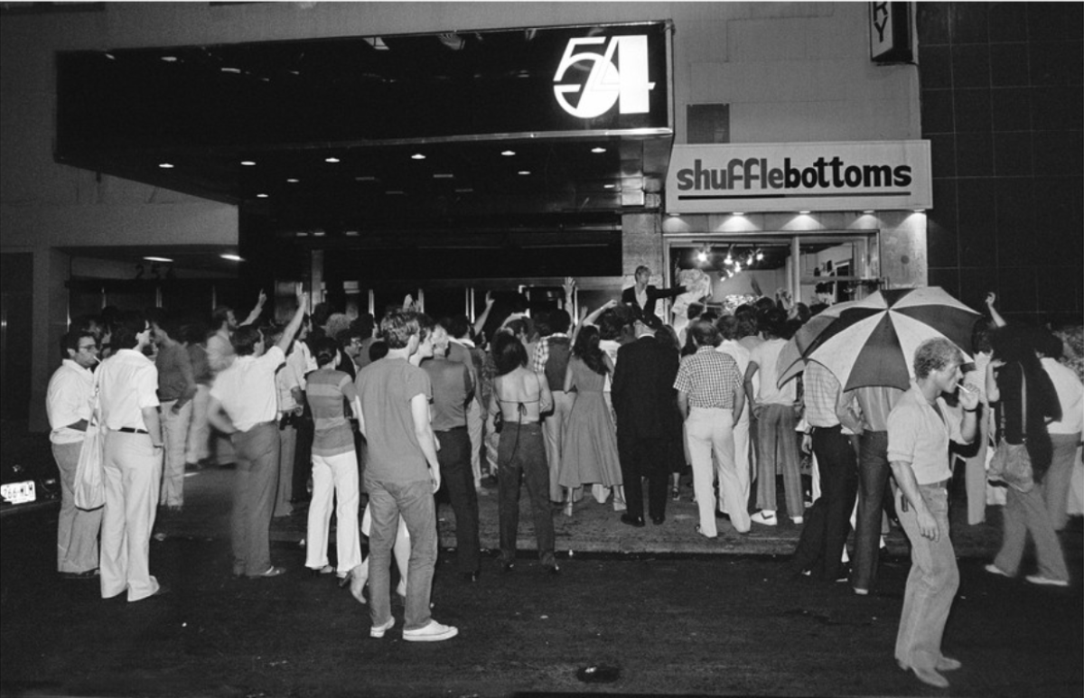 A crowd of people seen from behind at the doors of Studio 54.