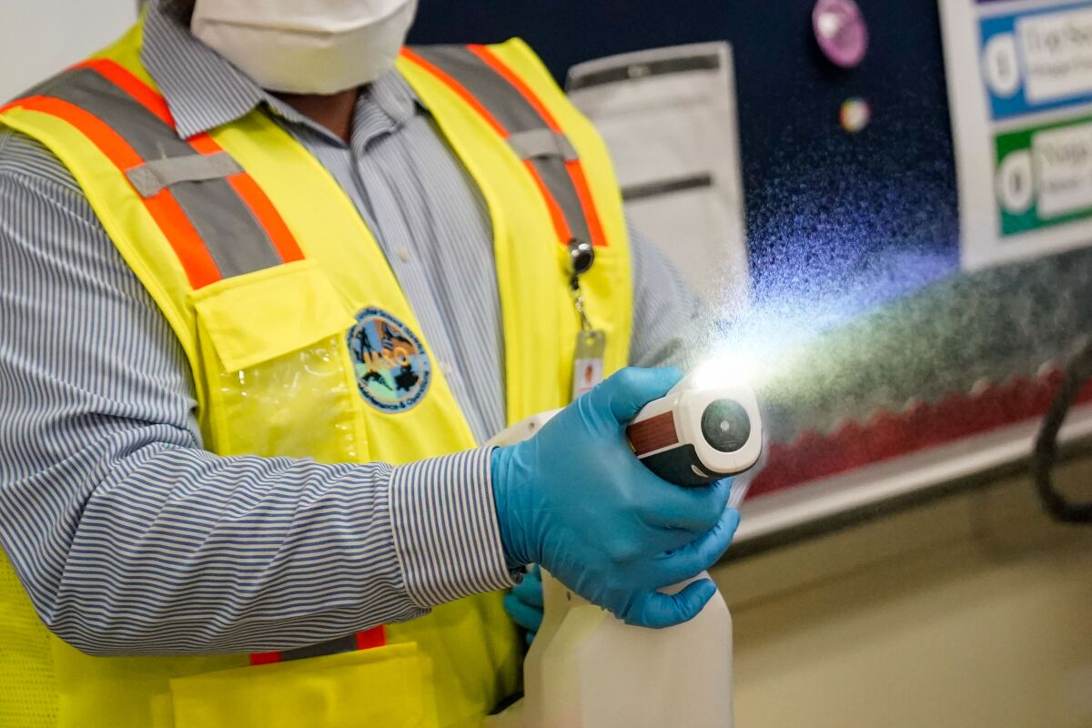 A worker sprays disinfectant in a classroom at Burbank Middle School.