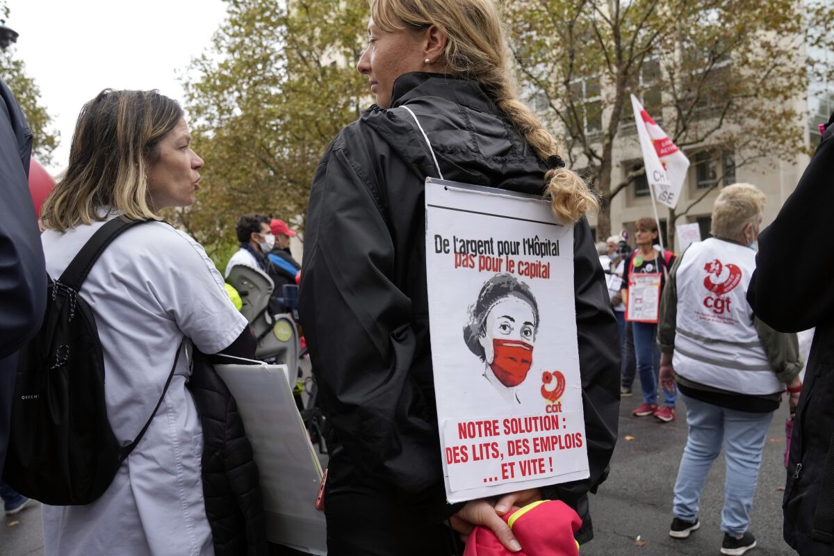 A medical worker holds a placard reading : "Money for Hospital, Not for the Capital, Our Solution Hospitals beds, Employs and quick", during a protest gathering outside the Health Ministry, in Paris, Tuesday, Sept. 14, 2021 against a law requiring them to get vaccinated by Wednesday or risk suspension from their jobs. The law is aimed at protecting patients from new surges of COVID-19. Most of the French population is vaccinated but a vocal minority are against the vaccine mandate. (AP Photo/Francois Mori)