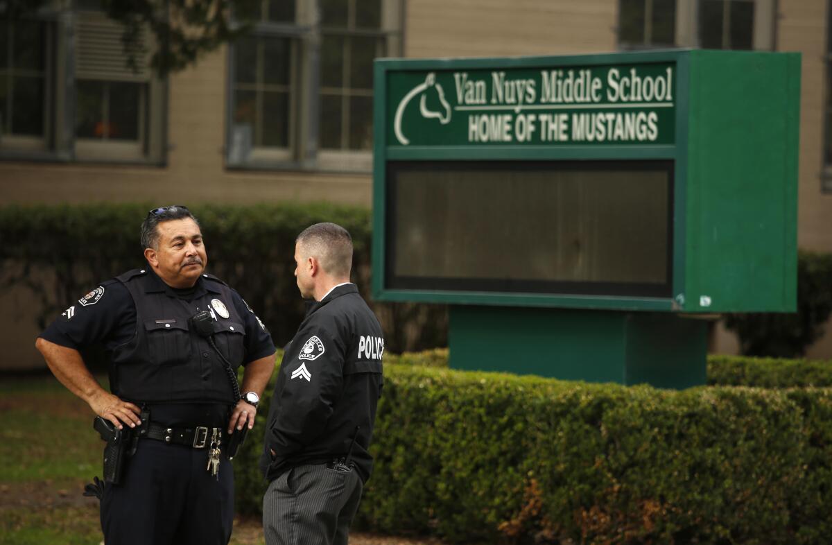 Police officers confer in front of Van Nuys Middle School
