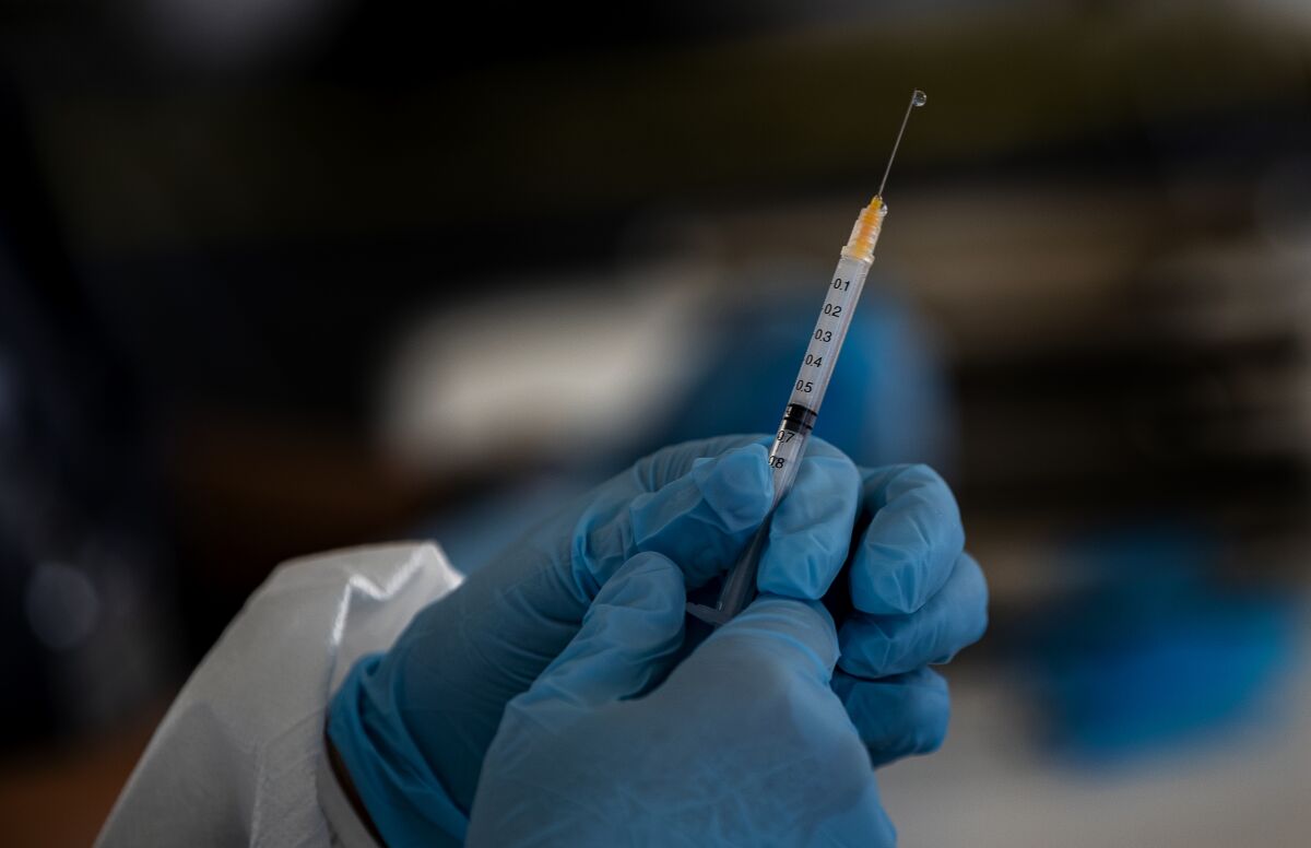 A health worker measures a dose of the Moderna vaccine.