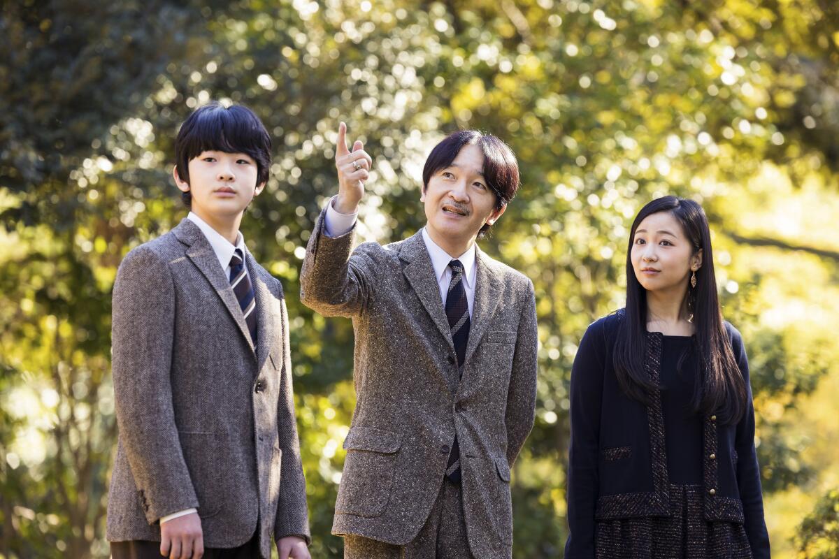 In this photo provided by Imperial Household Agency of Japan, Japan's Crown Prince Akishino, center, strolls with his son Prince Hisahito and his daughter Princess Kako at the garden of their Akasaka imperial property residence in Tokyo on Nov. 12, 2021. Akishino celebrates his 56th birthday Tuesday, Nov. 30, 2021. (Imperial Household Agency of Japan via AP)