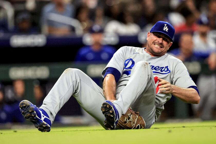 Los Angeles Dodgers relief pitcher Daniel Hudson falls to the ground as he injures himself while fielding a hit by Atlanta Braves' Ronald Acuna Jr. during the ninth inning of a baseball game Friday, June 24, 2022, in Atlanta. (AP Photo/Butch Dill)