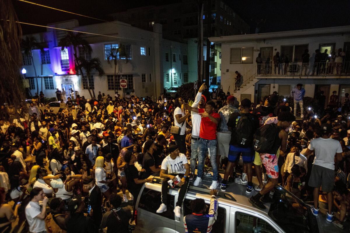 Crowds defiantly gather in the street while a speaker blasts music an hour past curfew in Miami Beach, Fla., on Sunday. 