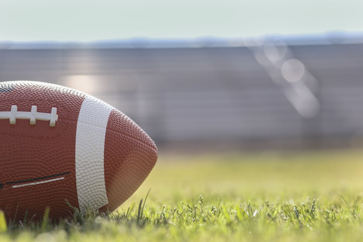Football on grass stadium on college or high school campus. Bleachers background.