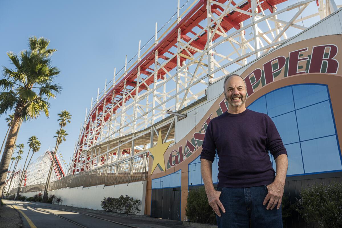 Ken Doctor stands beside a roller coaster on the Santa Cruz boardwalk.