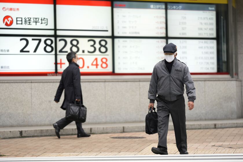 People walk by monitors showing Japan's Nikkei 225 index at a securities firm in Tokyo, Monday, Dec. 5, 2022. Asian shares were mostly higher and oil prices rose Monday after the European Union and the Group of Seven agreed on a boycott of most Russian oil and a price cap of $60 per barrel on Russian exports. (AP Photo/Hiro Komae)