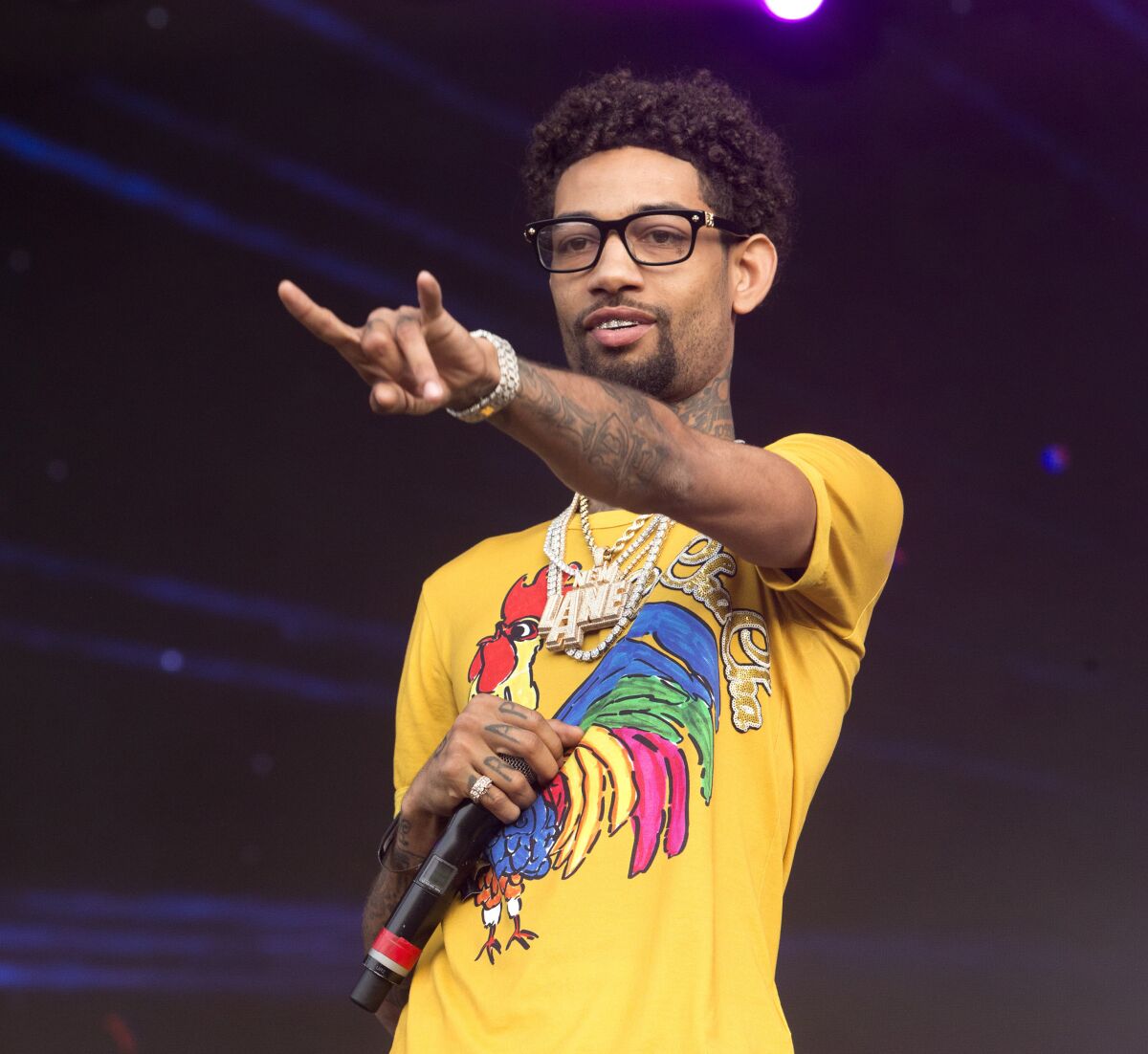 A rapper in a yellow T-shirt performs onstage.