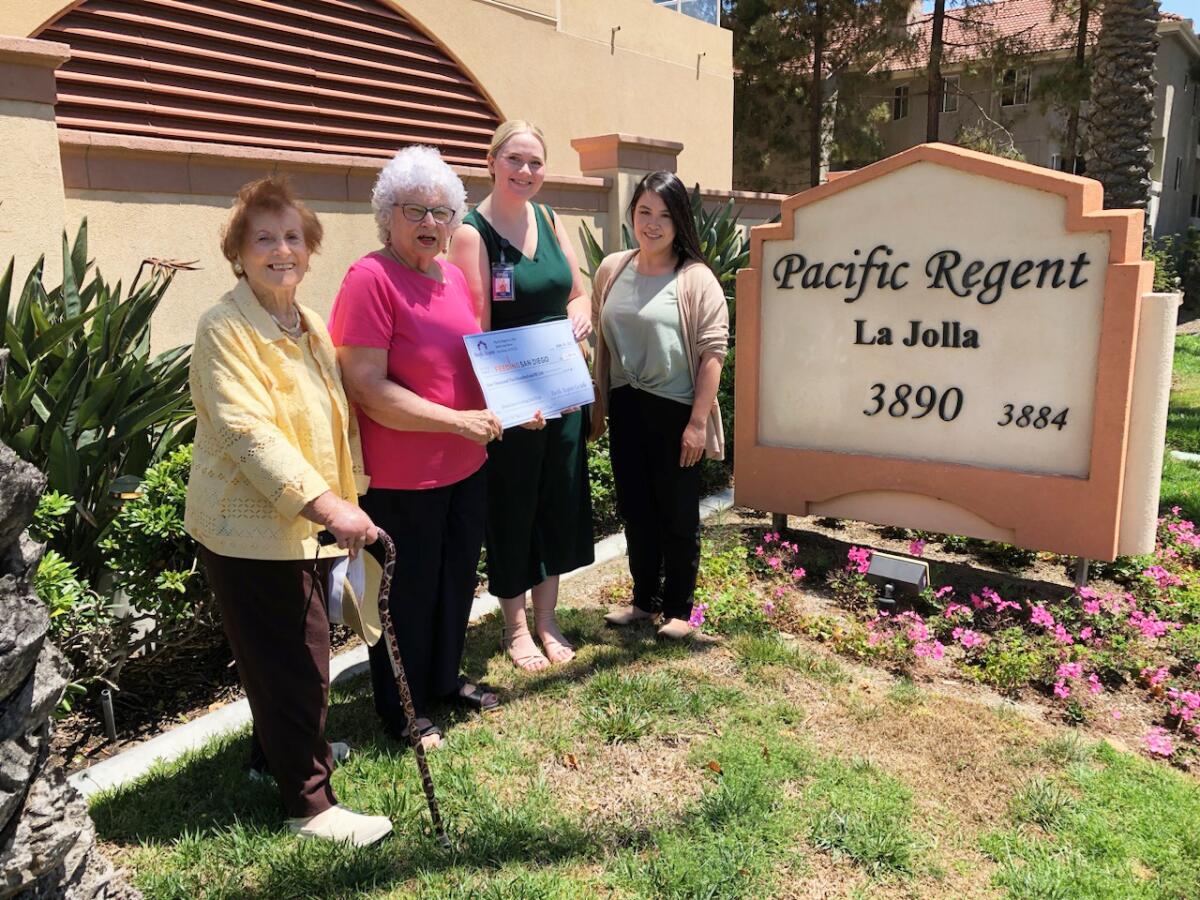 Tracy Walters-Chapman of Feeding San Diego (in green) accepts a check from Pacific Regent La Jolla.