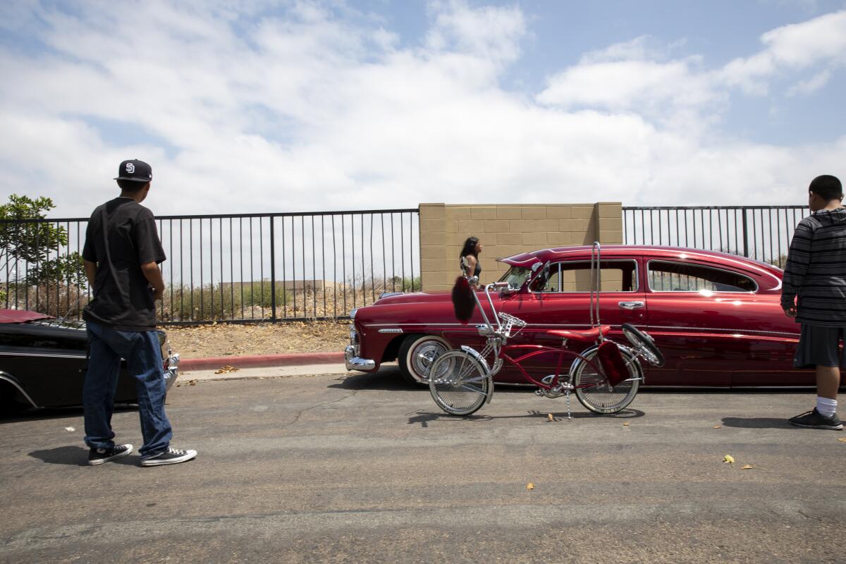From left, Isaac Rosales, 16, moves his lowrider bicycle next to a 1949 Hudson Brougham.