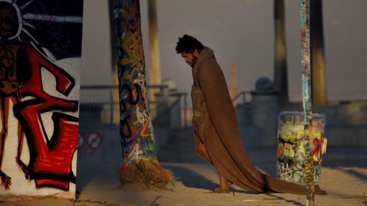 A homeless man walks around Venice Beach wearing a blanket November 6, 2017.