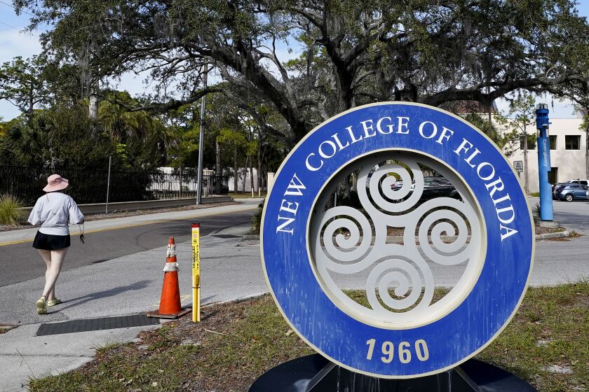 FILE - A student makes her way past the sign at New College of Florida, Jan. 20, 2023, in Sarasota, Fla. The New College of Florida trustees dominated by conservatives appointed by Gov. Ron DeSantis chose a new mascot on Thursday, June 1, 2023, for the Sarasota school: The Mighty Banyans. The tree mascot will replace one that has been in use since 1997, which is the mathematical formulation of the Null Set. (AP Photo/Chris O'Meara, File)