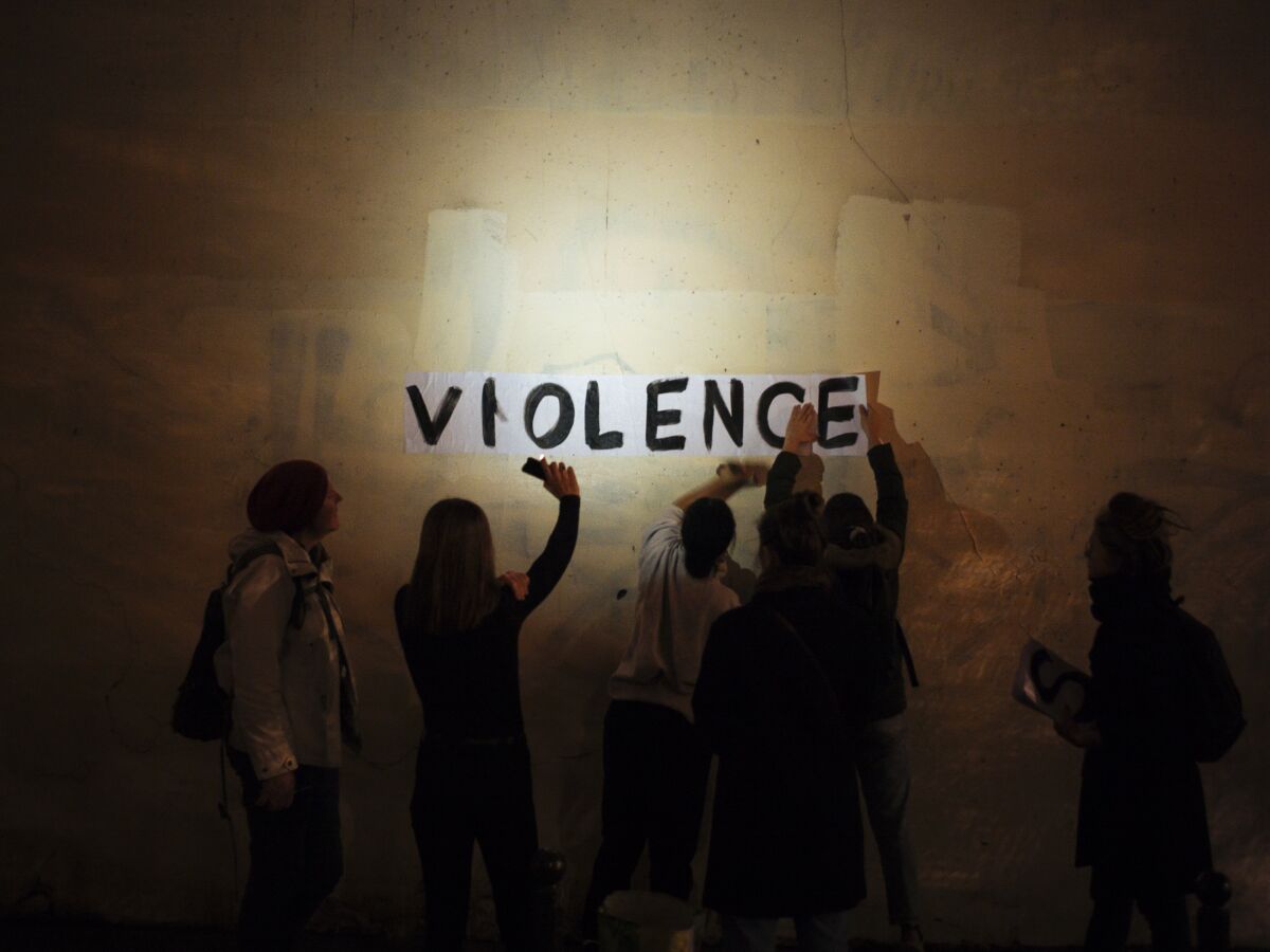 FILE- In this Oct. 31, 2019 photo, the word "violence" is pasted onto a wall by a group of women in a dark street in Paris. Three women in France were found dead on New Year's Day, allegedly killed by their partners, despite years of efforts by President Emmanuel Macron's government to rein in deadly domestic violence. (AP Photo/Kamil Zihnioglu, File)